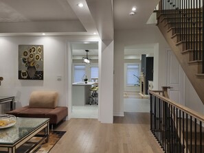 A modern living room with a sofa, a glass coffee table, and a painting on the wall. - Entire Cozy Home at the heart of Richmond Hill! (Richmond Hill)