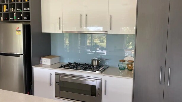 Une cuisine moderne équipée d’un four encastré, d’une cuisinière à gaz et d’un réfrigérateur en acier inoxydable.