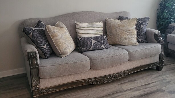 A grey upholstered sofa with ornate wooden legs, positioned against a plain wall with two round mirrors. - 29-day min stays, In-unit laundry, and reliable WiFi. Corporates stays welcome (Bel Aire)