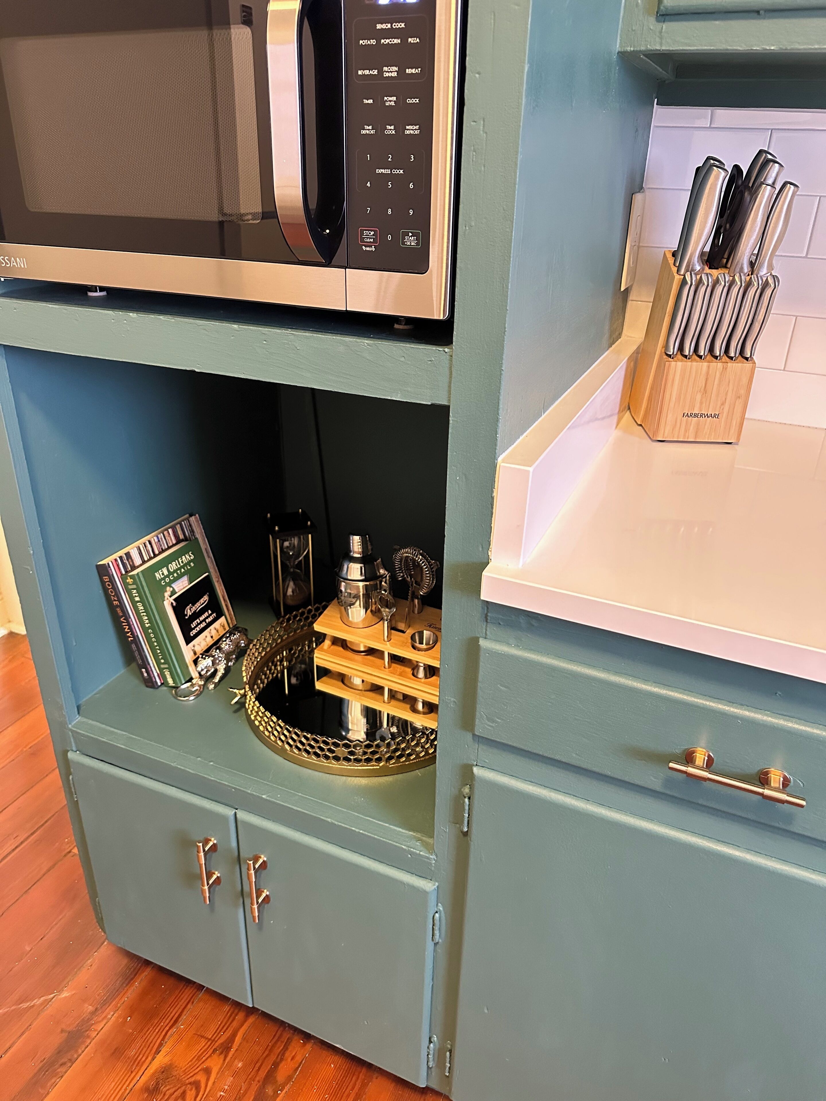 Una cocina con microondas, un bloque de cuchillos y un libro sobre la encimera.