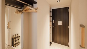 A hallway with a wooden door, a coat rack, and a shoe rack. - HOTEL SHUTEC (Kagoshima)