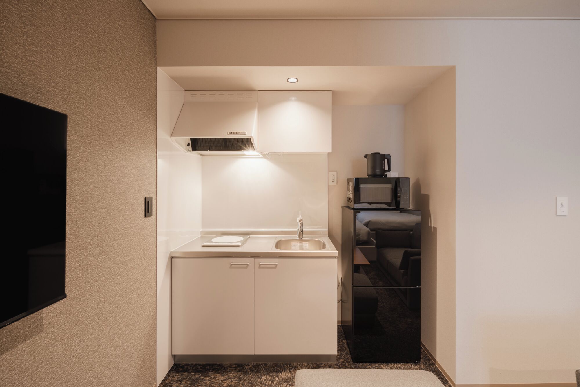 Una cocina compacta con microondas, estufa y lavamanos.