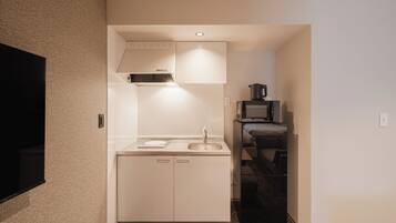 Una cocina compacta con microondas, estufa y lavamanos.