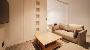 A compact living space with a sofa, a small table, and a wardrobe with multiple compartments. - HOTEL SHUTEC (Kagoshima)