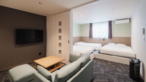 A hotel room with a sofa, a small table, a TV, two beds, a mirror, and a trash bin. - HOTEL SHUTEC (Kagoshima)