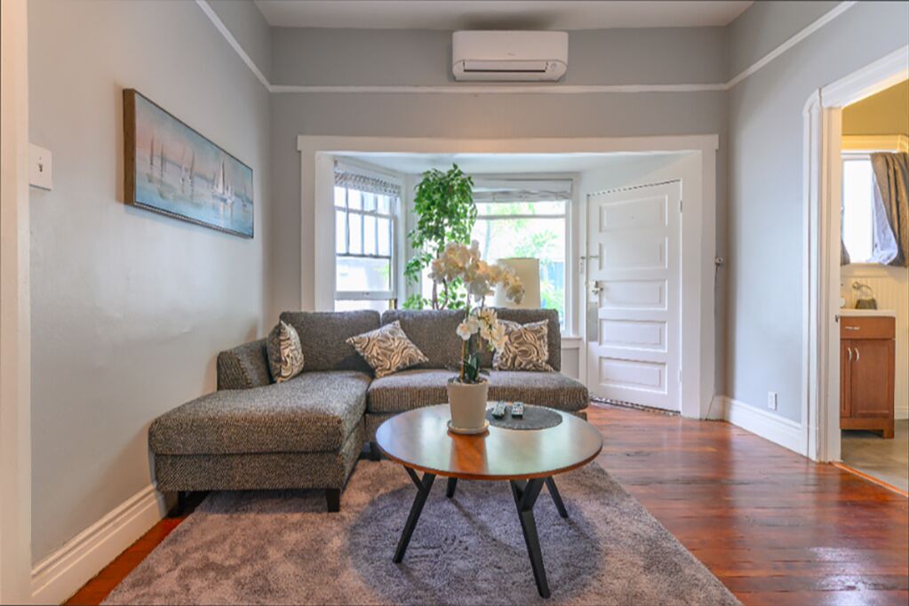 A living room with a sectional sofa, a round coffee table, and a potted plant.