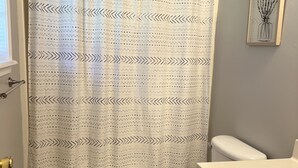Ein Badezimmer mit Duschvorhang, Toilette, Waschbecken und einem gerahmten Bild an der Wand.