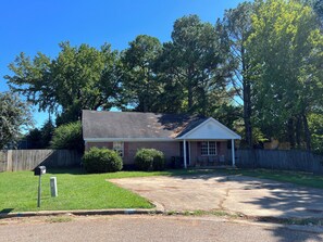A single-story house with a sloped roof, a front porch, and a mailbox.