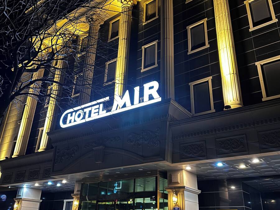 Un hôtel reconnaissable à son grand panneau « HÔTEL MLR », à ses larges fenêtres et à ses colonnes d’architecture classique.