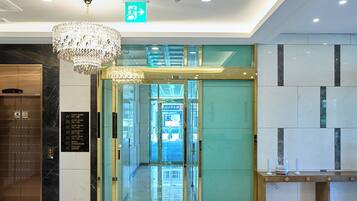 Un hall de hotel con una araña, una recepción y una puerta de cristal que da a la entrada.