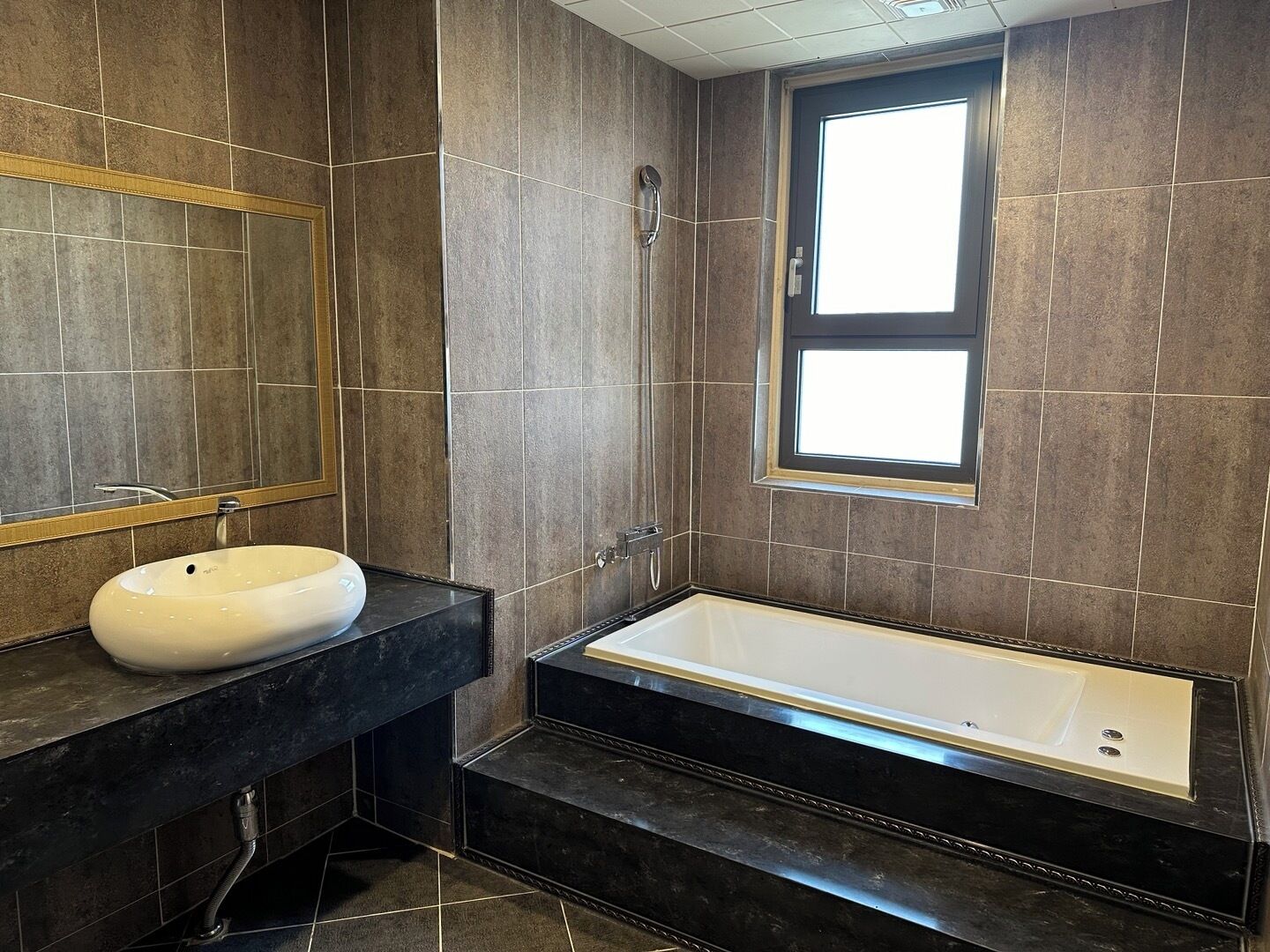 Un baño moderno con una bañera grande, un lavabo redondo y una ventana que proporciona luz natural.