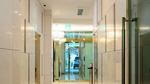 A corridor with marble flooring and glass doors leading to a lobby area. - mir hotel (Sokcho)