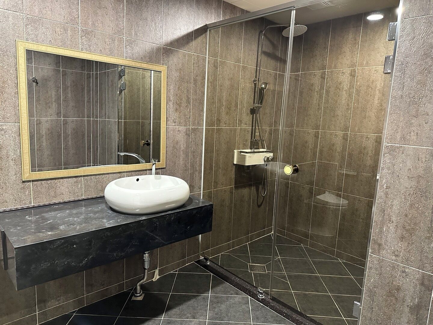 Une salle de bain moderne avec un lavabo blanc, un miroir et une douche séparée par une paroi en verre.