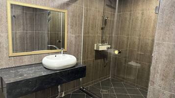 A modern bathroom with a white sink, a mirror, and a glass-enclosed shower area.