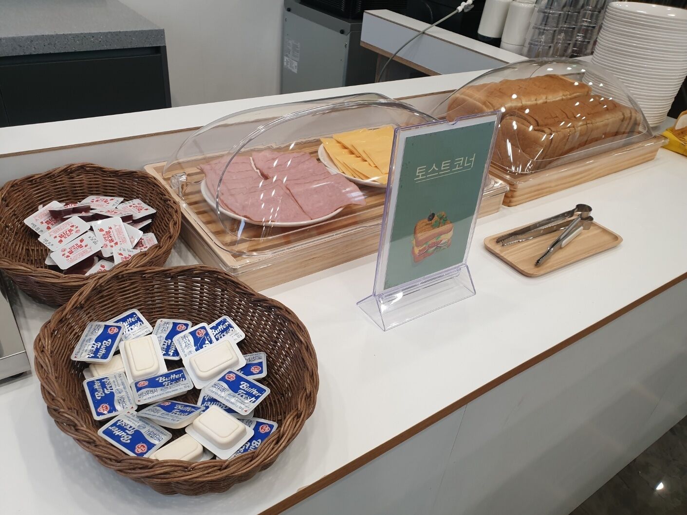 A buffet counter with various food items, including wrapped meats, cheeses, and butter tubs.