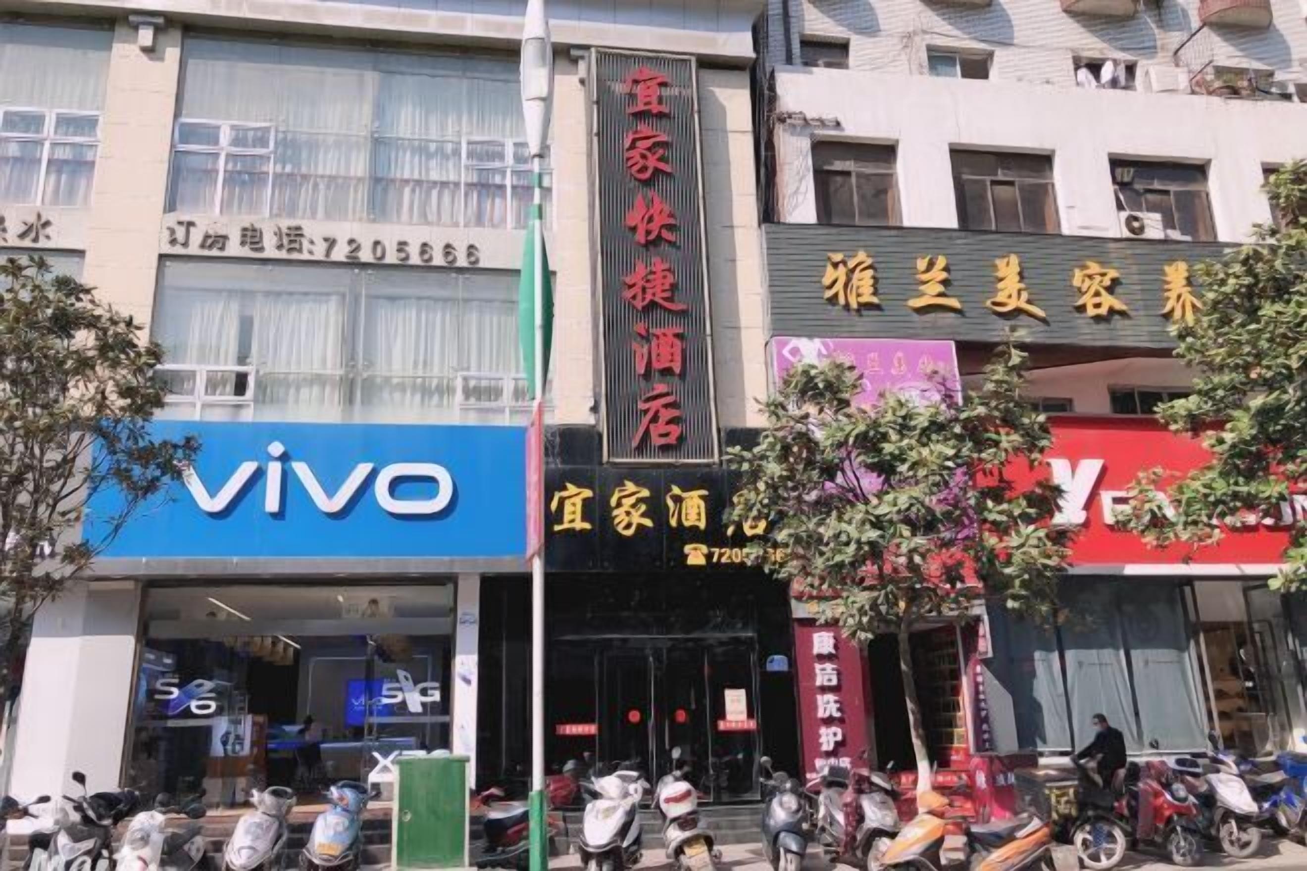 A building with a 'vivo' sign, a '家家快捷酒店' sign, and a '雅兰美美容' sign.