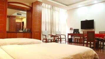 A hotel room with two beds, a TV, a desk, and a chair.