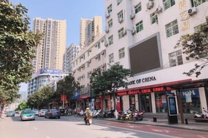 Una calle con edificios, coches estacionados y una motocicleta.