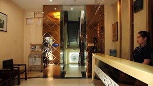 A hotel reception area with a reception desk, a seating area with chairs, and a decorative wall with certificates. - IKEA Express Hotel Xunyang (Xunyang)