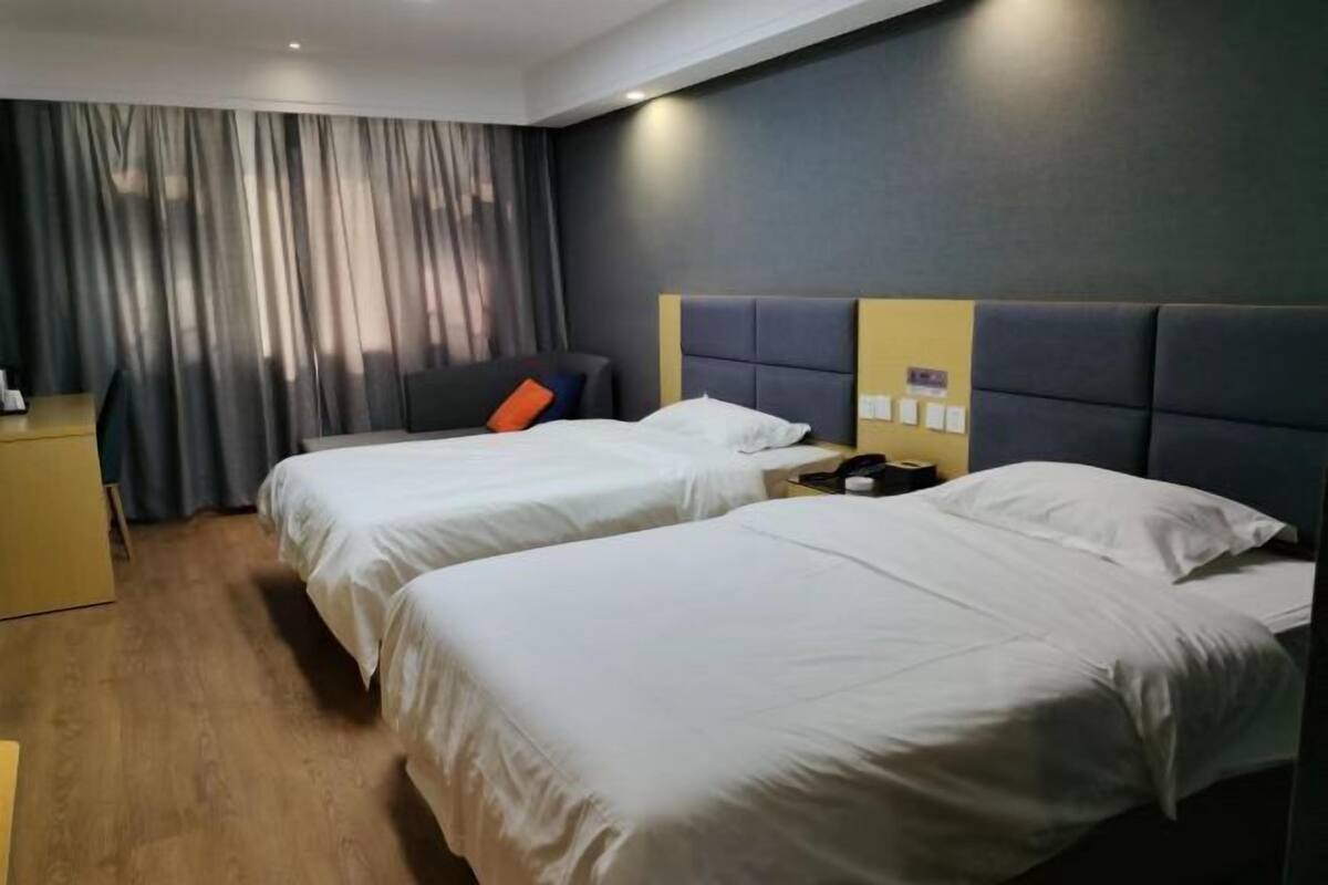 A hotel room with two beds, a desk, and a chair.