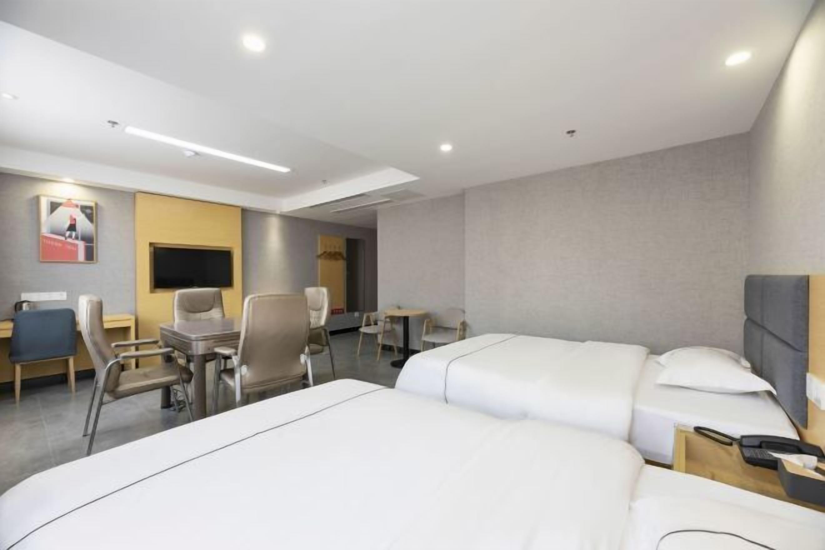 Una habitación de hotel con dos camas, un escritorio, una silla, un televisor y una pequeña mesa.