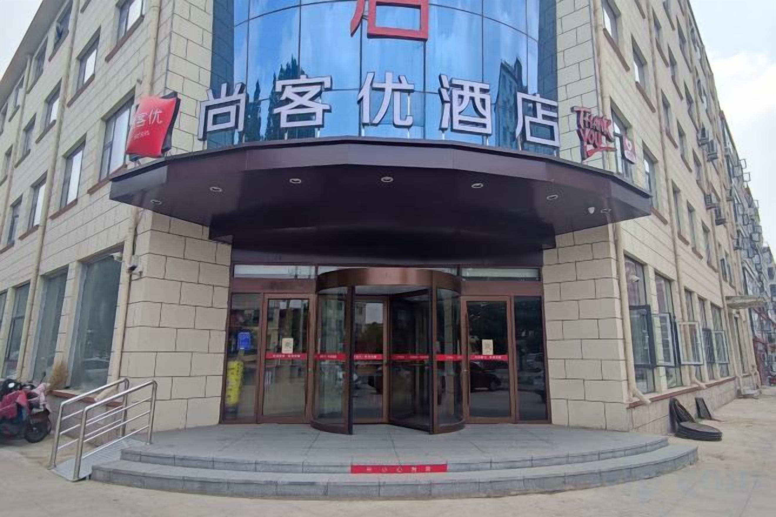 A hotel entrance with a curved facade, glass doors, and a sign above the entrance.