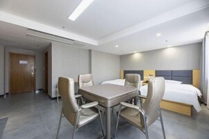 Quarto de hotel com cama, mesa e quatro cadeiras.