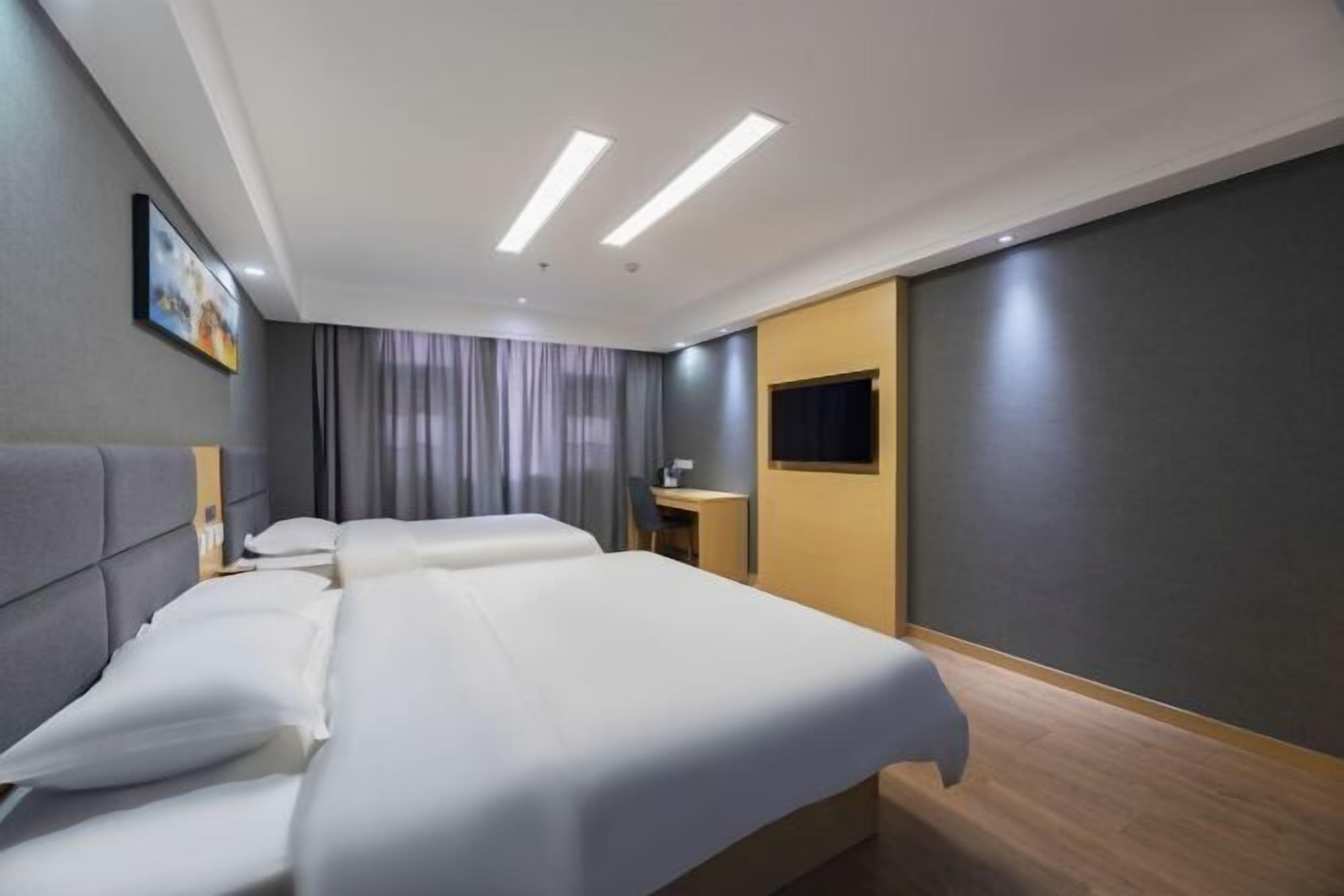 Habitación de hotel con una cama grande, un escritorio, una silla y un televisor en la pared.