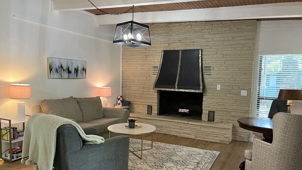 A living room with a fireplace, a sofa, a coffee table, and a patterned rug.