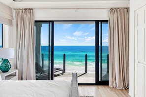 Une chambre dotée d’une grande porte-fenêtre coulissante donnant sur un balcon avec vue sur l’océan.