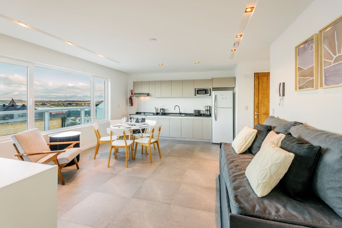 Una cocina moderna con vistas, una zona de comedor con sillas y un sofá con cojines.