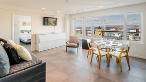Una sala de estar moderna con comedor, ventanas amplias con vista a la ciudad y una zona de estar acogedora.