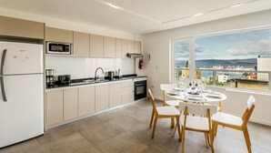 Una cocina moderna con comedor, ventanas amplias y vistas al mar.
