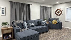 Ein modernes Wohnzimmer mit einem Ecksofa, einem kleinen Sessel und Holzboden.