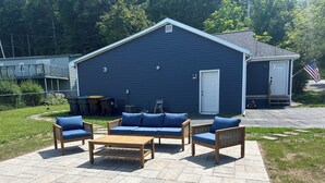 Eine Terrasse mit blauer Sofagarnitur, einem Holztisch und Korbstühlen.