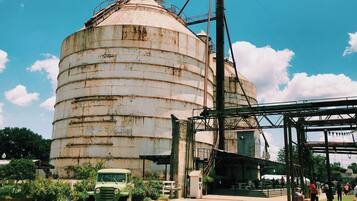 A large, rusted industrial silo with a green truck parked in front.