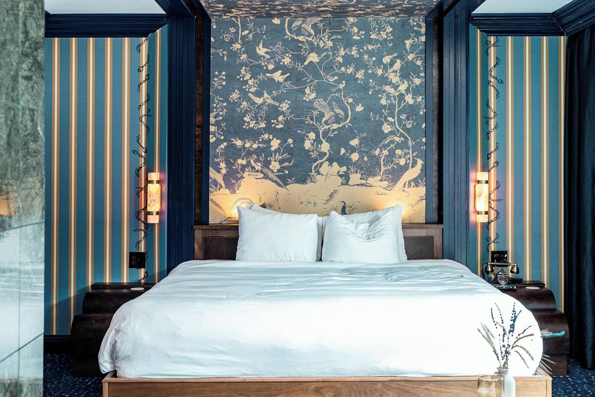 A modern hotel room with a large bed, a marble floor, and a unique ceiling design.