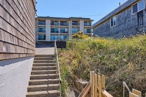 A building with a multi-story structure, a staircase leading to a lower level, and a wooden fence.