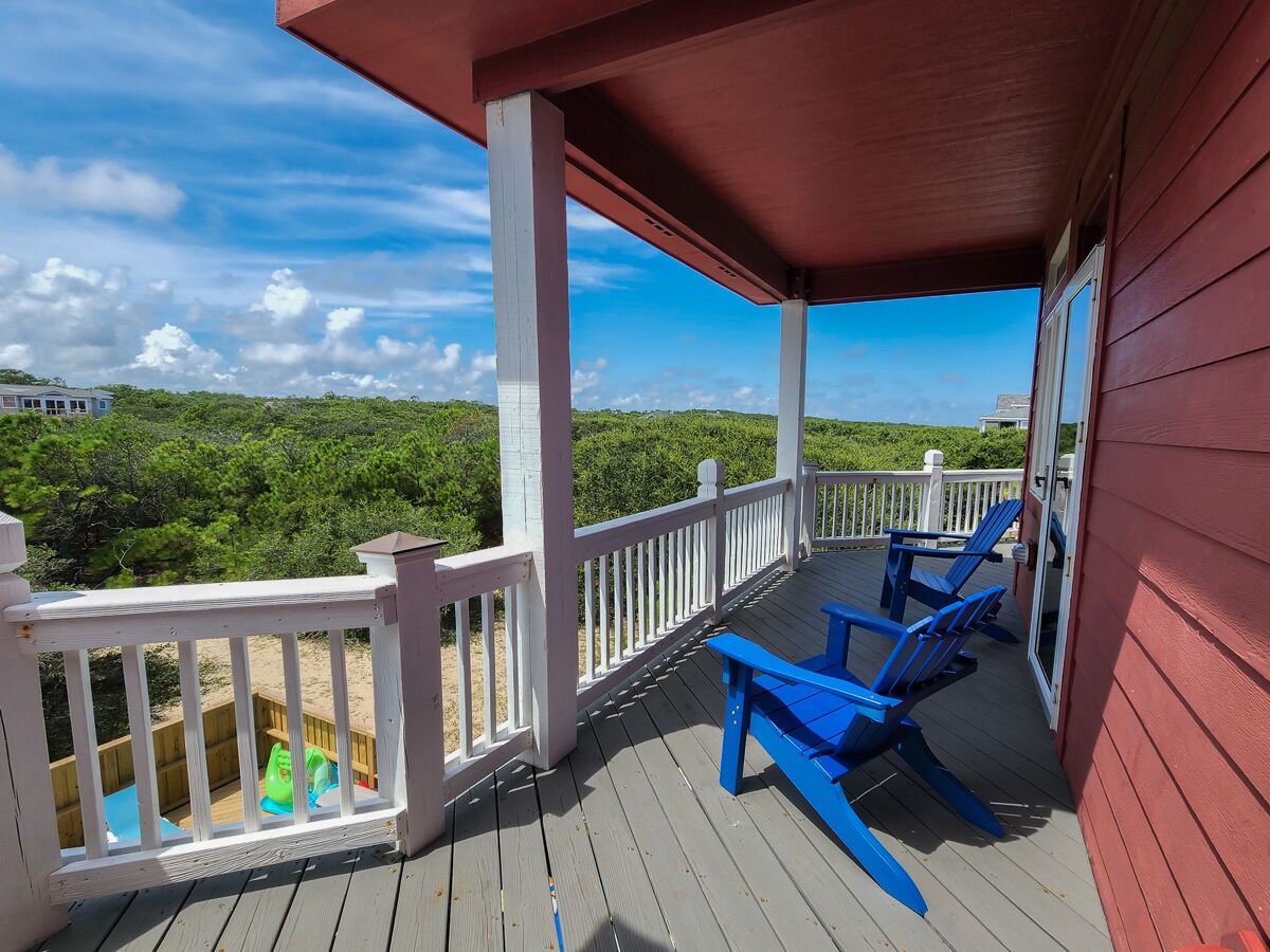 A covered deck with blue chairs and a small pool area.
