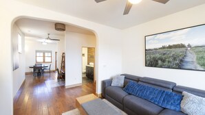 A modern living room with hardwood flooring, a gray sofa, a blue throw blanket, and a large landscape painting on the wall. - Main Street Carbondale Townhome.  Super Convenient.
 (Carbondale)