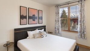 A bedroom with a large bed, a nightstand, a window with curtains, and three framed pictures on the wall. - Main Street Carbondale Townhome.  Super Convenient.
 (Carbondale)