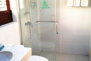 A bathroom with a glass shower enclosure, a white sink, and a toilet.