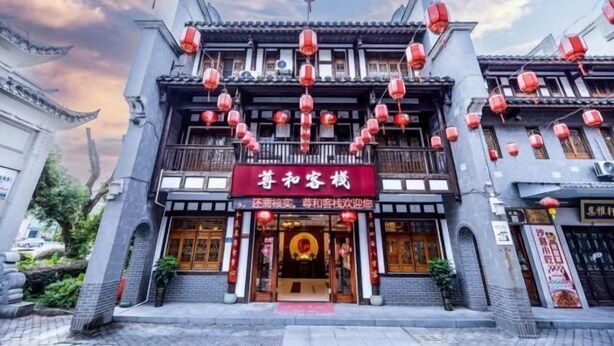 A traditional building with a red sign, multiple floors, and red lanterns. - Sanming Zunhe Inn (Shaxian Snack Culture City) (Sanming)