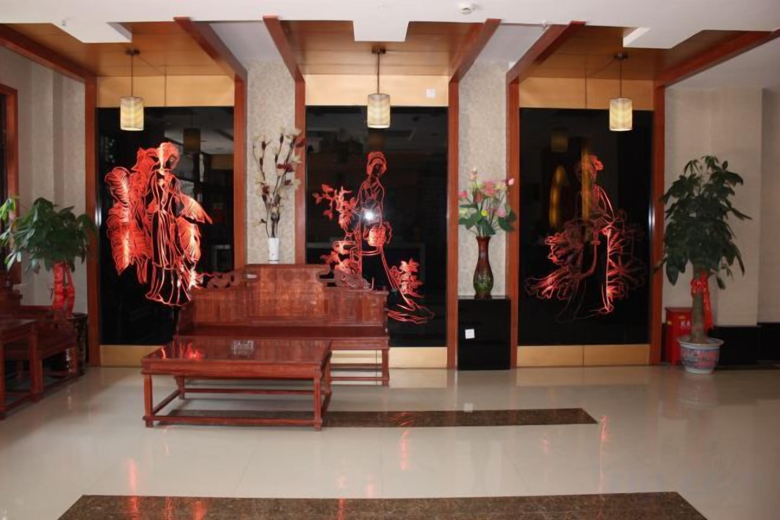A dining area with a wooden table and chairs, a black wall with red artwork, and potted plants.