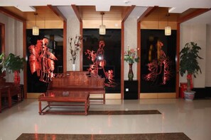 A dining area with a wooden table and chairs, a black wall with red artwork, and potted plants.