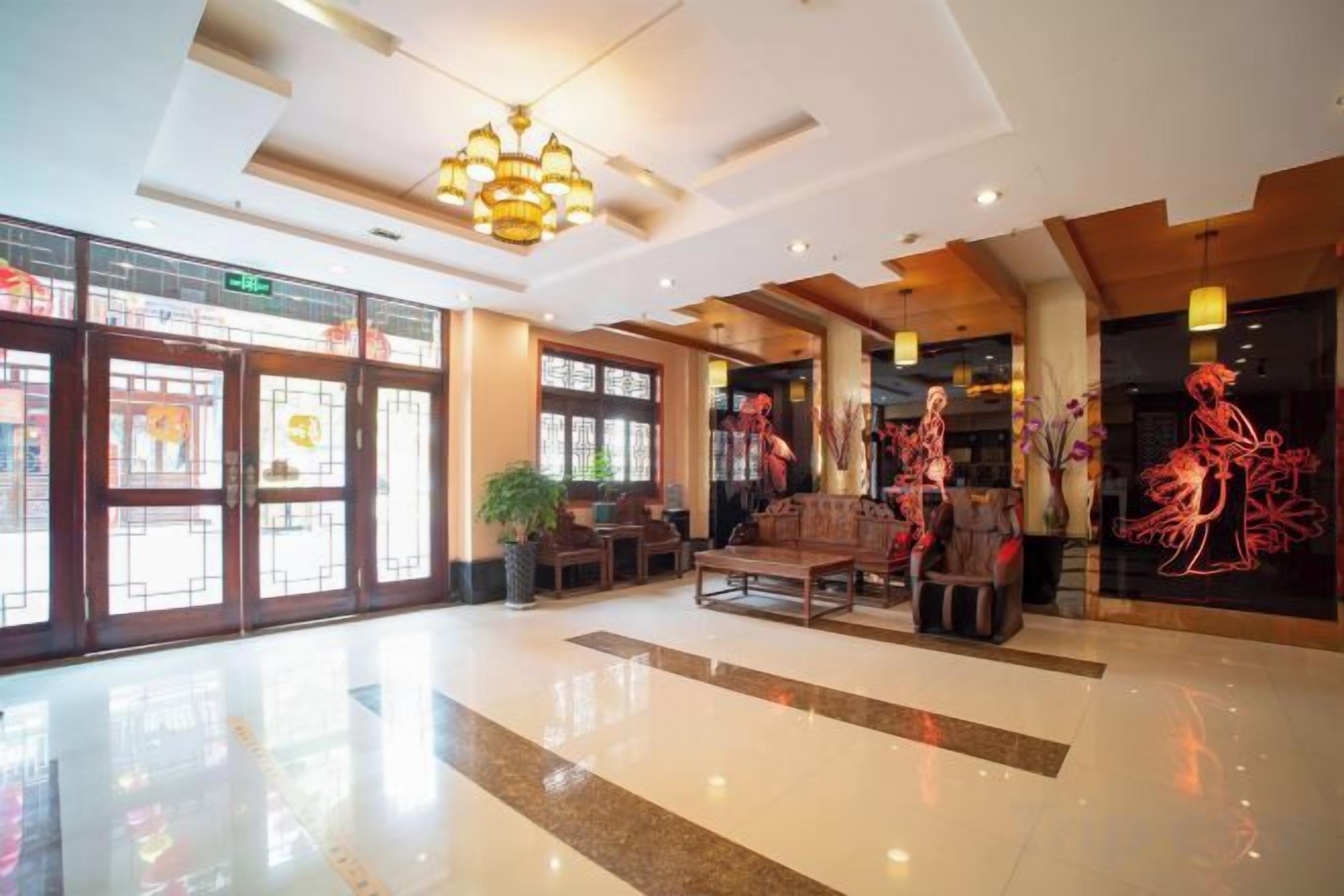 A spacious lobby with a polished floor, a chandelier, and a seating area with a sofa and chairs.