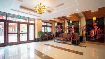A spacious lobby with a polished floor, a chandelier, and a seating area with a sofa and chairs.