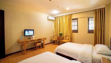A hotel room with two beds, a desk with a chair, a television, and curtains.