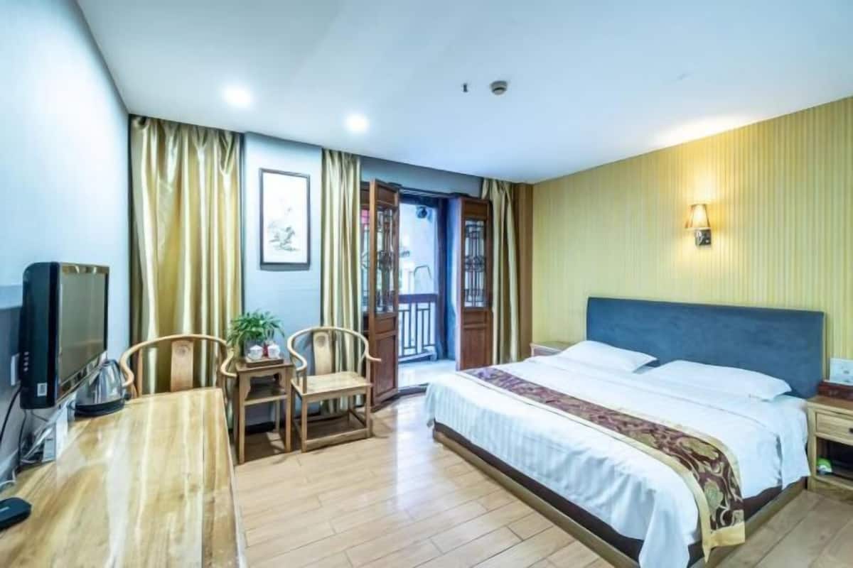 Ein Hotelzimmer mit einem Bett, einem Schreibtisch mit Stuhl, einem Fernseher und einem kleinen Tisch mit Pflanze.