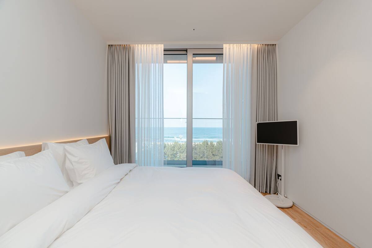 Habitación de hotel con una cama grande, televisor y vista al mar.